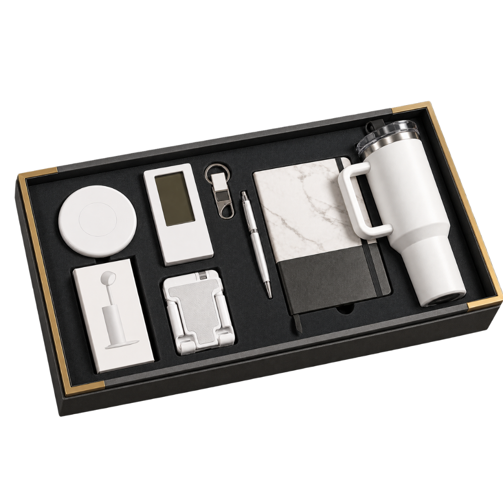 A premium black executive gift box containing a white tumbler, marble notebook, pen, digital clock, keychain, and phone stand.