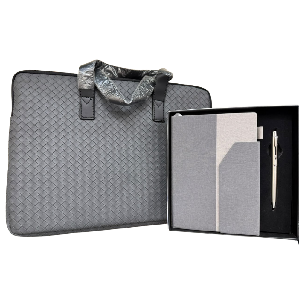 A grey woven laptop briefcase next to a black gift box containing a grey notebook and a silver pen.