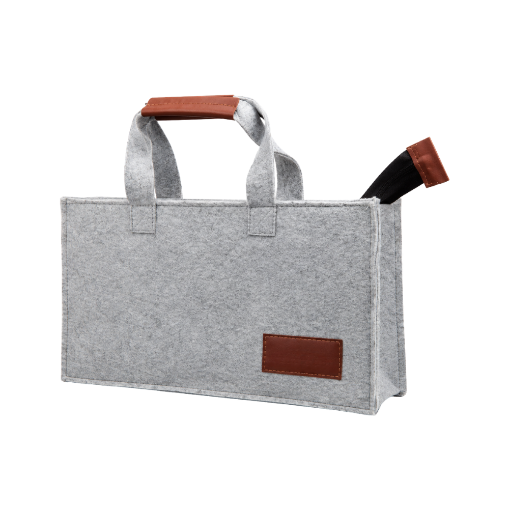 A grey felt tote bag with brown faux leather handle grips and a blank leatherette branding patch on the front.