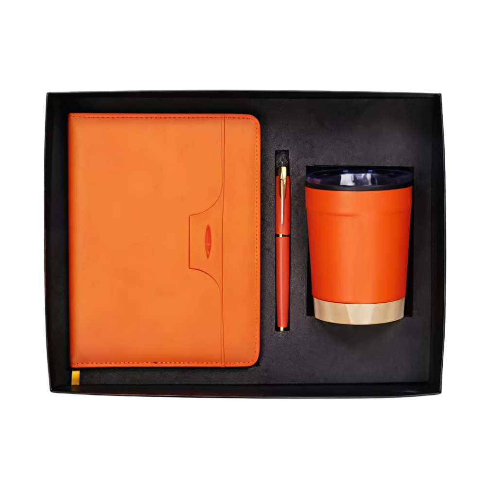 Top-down view of an orange corporate gift set containing a notebook, pen, and tumbler in a black presentation box.