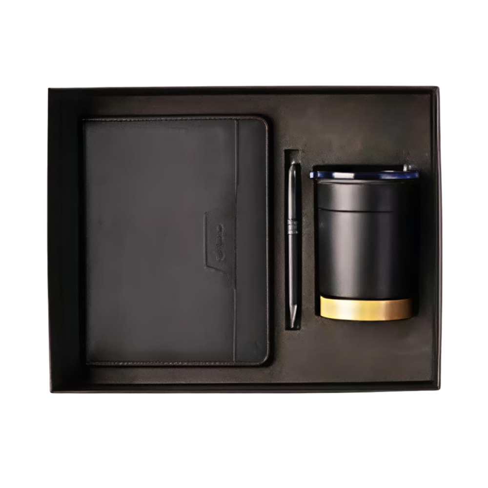 Top-down view of an executive gift set in a black box containing a black notebook, a black pen, and a black mug with a gold base.