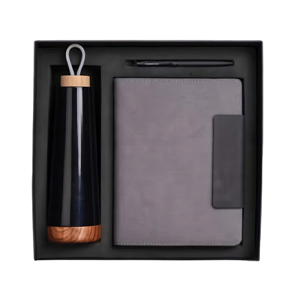 Top-down view of a black gift box containing a vacuum-insulated bottle with a wood-grain base, a gray notebook, and a black pen.