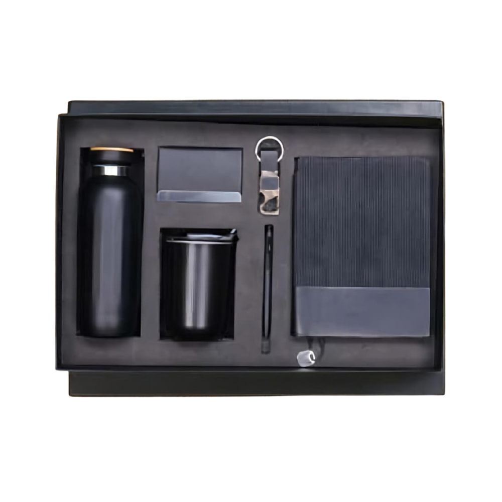 Top-down view of a 5-piece executive gift set in a black box, including a bottle, tumbler, notebook, pen, and keychain.