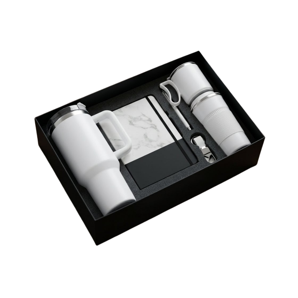 A premium gift set in a black box containing a white tumbler, marble notebook, pen, and keychain.