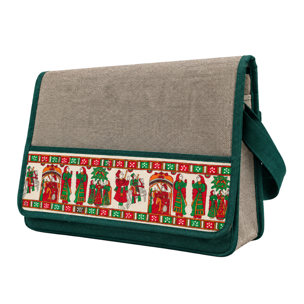 A side-angle view of a structured messenger bag with a grey fabric body, green trim, and a colorful traditional Indian folk art print band.